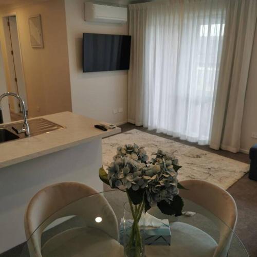 a vase of flowers on a glass table in a kitchen at Comfort and Peace at The Lakes in Tauranga
