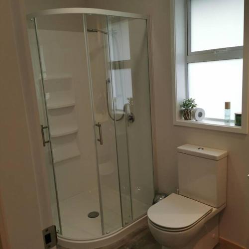 a bathroom with a toilet and a glass shower at Comfort and Peace at The Lakes in Tauranga