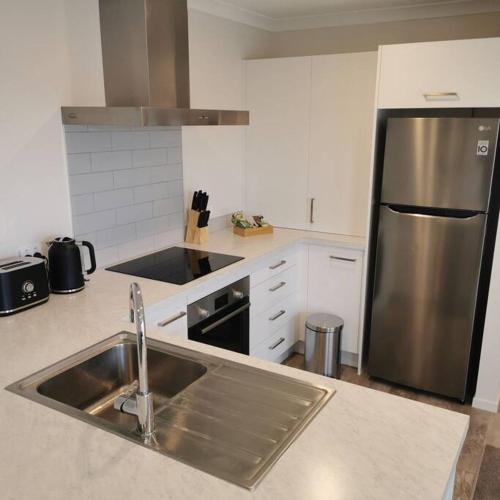 a kitchen with a sink and a stainless steel refrigerator at Comfort and Peace at The Lakes in Tauranga