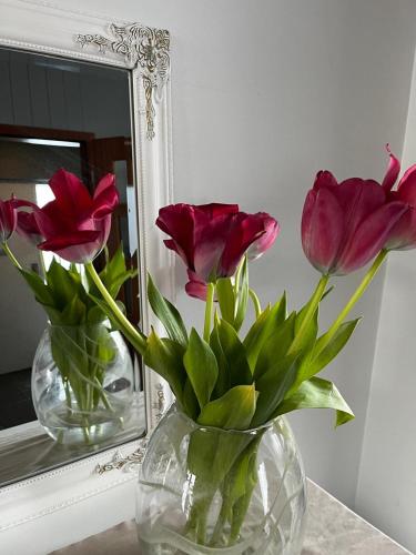 two vases with flowers in them sitting on a table in front of a mirror at Lágholt 16 in Stykkishólmur