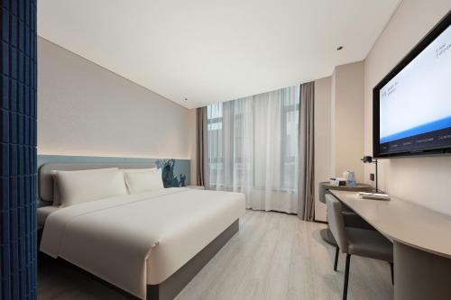 una camera con letto e TV a schermo piatto di Atour Light Hotel Wuxi Taihu Lake Expo Center Financial Street a Wuxi