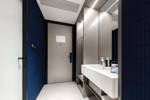 un bagno con un lavandino bianco e uno specchio di Atour Light Hotel Wuxi Taihu Lake Expo Center Financial Street a Wuxi