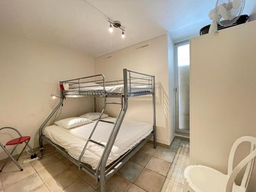 Ce lit superposé se trouve dans une petite chambre dotée d'une fenêtre. dans l'établissement Appartement moderne, 2 pièces cabine, terrasse et véranda, proche plage, parking privé - FR-1-338-133, à Sète