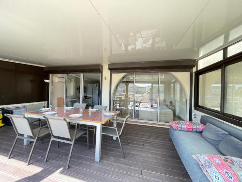 une salle à manger avec une table, des chaises et un canapé dans l'établissement Appartement moderne, 2 pièces cabine, terrasse et véranda, proche plage, parking privé - FR-1-338-133, à Sète