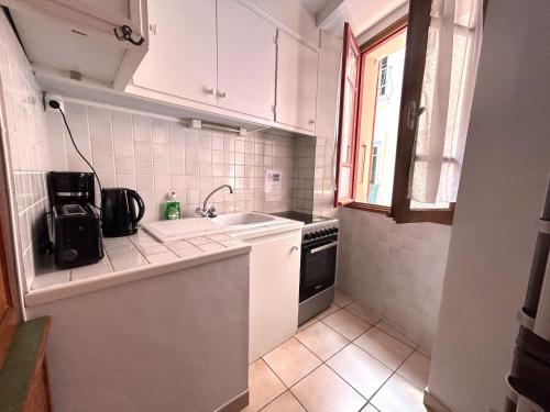 une petite cuisine avec des armoires blanches et un évier dans l'établissement Appartement F3 charmant au cœur de Collioure, à 2 pas de la plage et des commerces - FR-1-309-284, à Collioure