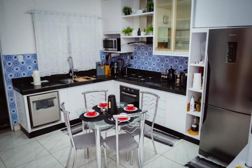 uma cozinha com mesa, cadeiras e geladeira em Casa de Gente Feliz 2 em Cuiabá