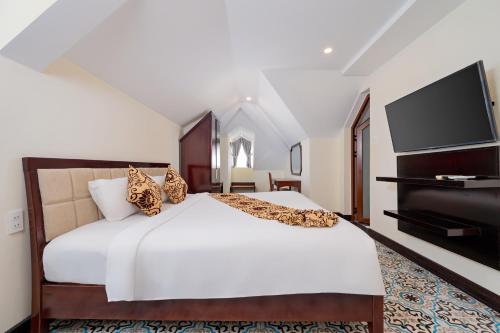 a bedroom with a bed and a flat screen tv at Hoi An Canal House Riverside By Haviland in Hoi An