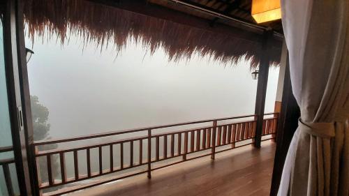 a balcony with a large window with a view at KHIRI HOUSE &Café Farm ดอยช้างเชียงรายที่พักอาข่าเรียวกังสไตล์กลางหมู่บ้านดอยช้าง in Ban Rong Than