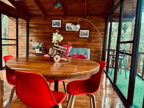 a dining room with a wooden table and red chairs at Casa Alfeñique in Villa del Carbón
