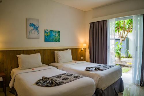 two beds in a hotel room with a window at Royal Regantris Villa Karang in Gili Air