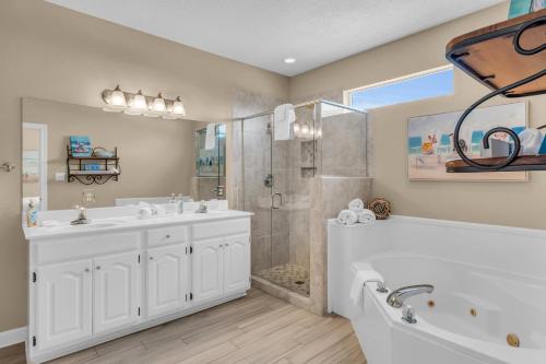 a bathroom with two sinks and a tub and a shower at Dandy Sandy in Gulf Shores