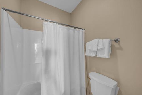 a bathroom with a white shower curtain and a toilet at Dandy Sandy in Gulf Shores