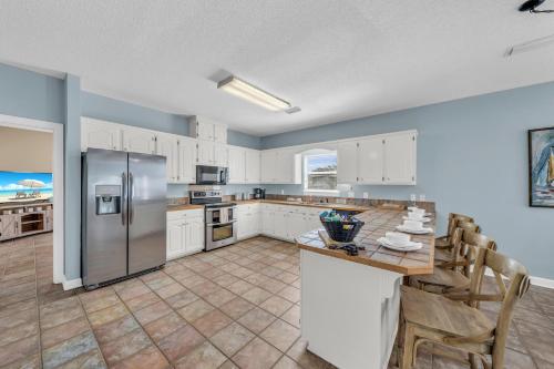 a kitchen with white cabinets and a stainless steel refrigerator at Dandy Sandy in Gulf Shores