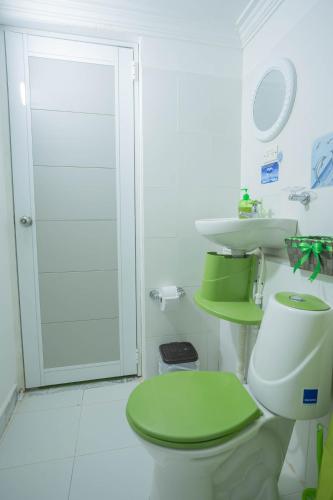 a white bathroom with a green toilet and a sink at Posada Stoy Places in Providencia
