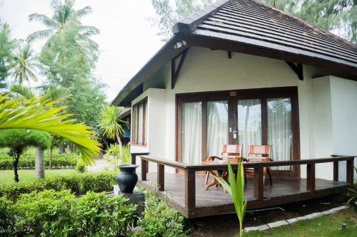 a house with a wooden deck with two chairs at Royal Regantris Villa Karang in Gili Air