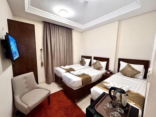 a hotel room with two beds and a chair at Knooz Aldiafah in Makkah
