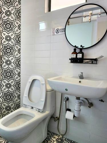 a bathroom with a toilet and a sink and a mirror at Georgetown AY Hotel in George Town