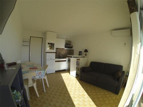 Il dispose d'une cuisine et d'un salon avec un canapé et une table. dans l'établissement Studio Cabine Climatisé 3 Couchages avec Terrasse et Parking Privé - Port Camargue - FR-1-731-92, au Grau-du-Roi