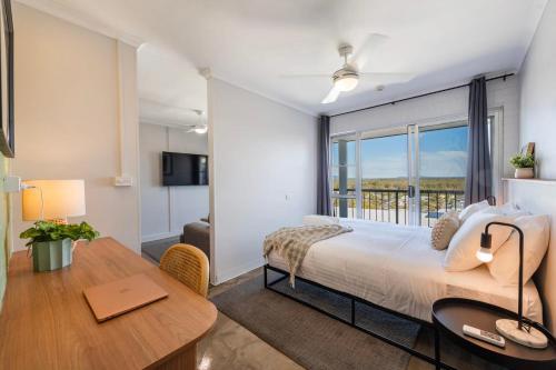 Un dormitorio con una cama y un escritorio y una ventana. en Yamba Views 10 - Oceanstays, en Yamba
