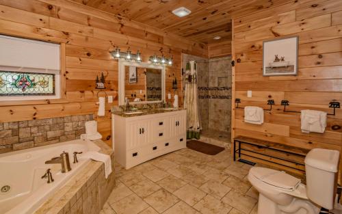 ein Blockhausbad mit einer Badewanne und einem WC in der Unterkunft Beartastic Mountain View Lodge in Gatlinburg