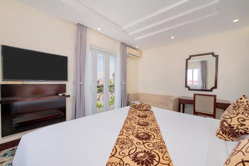 a hotel room with a bed and a television at Hoi An Canal House Riverside By Haviland in Hoi An