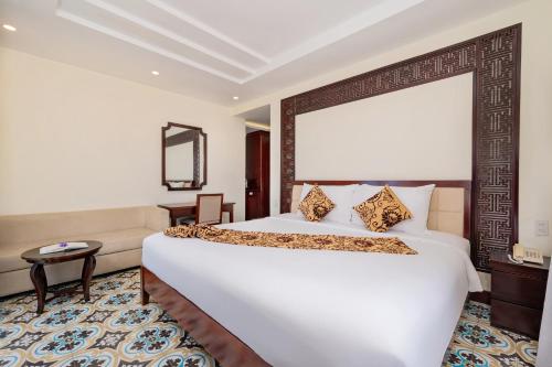 a bedroom with a large white bed and a couch at Hoi An Canal House Riverside By Haviland in Hoi An
