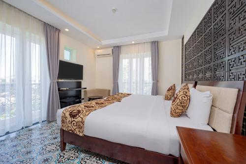 a hotel room with a bed and a television at Hoi An Canal House Riverside By Haviland in Hoi An