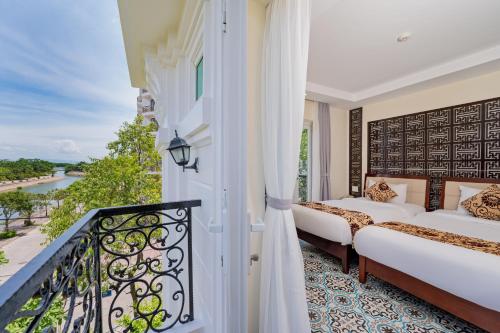 a room with two beds and a balcony at Hoi An Canal House Riverside By Haviland in Hoi An