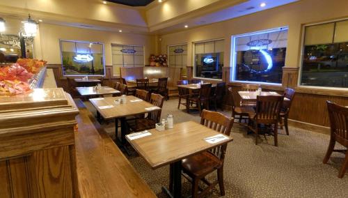 a restaurant with wooden tables and chairs and a piano at Travelodge by Wyndham Ottawa East in Ottawa