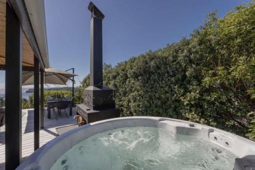 a hot tub with a grill in a backyard at Hosts on the Coast Hahei Moana in Hahei