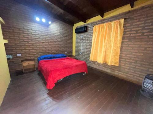 a room with a red bed in a brick wall at Alojamiento en cataratas in Puerto Iguazú