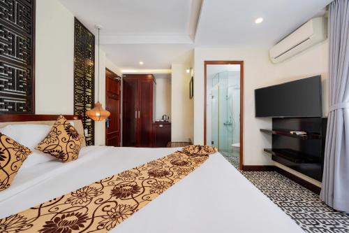 a hotel room with a bed and a flat screen tv at Hoi An Canal House Riverside By Haviland in Hoi An