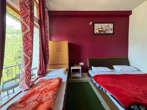 two beds in a room with a red wall at THE GROOVE GARDEN DHANOLTi in Dhanaulti