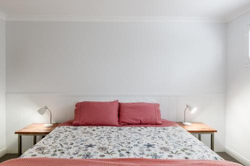 a bedroom with a bed with pink pillows and two tables at Karri Keep - Spacious 3 Bedroom Town Villa in Margaret River Town