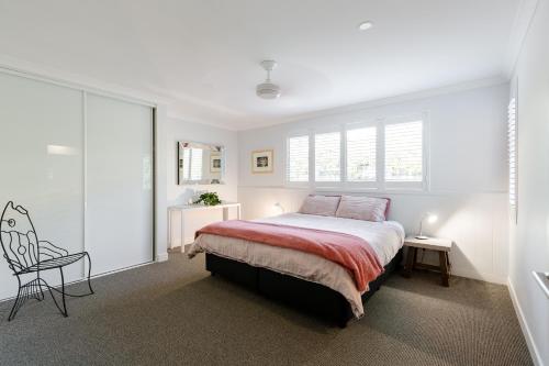 a white bedroom with a bed and a chair at Karri Keep - Spacious 3 Bedroom Town Villa in Margaret River Town