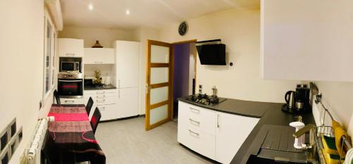 une cuisine avec des armoires blanches et une table et des chaises dans l'établissement Garden party event, à Nogent-sur-Oise