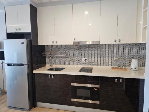 a kitchen with white cabinets and a refrigerator at Sirin Exclusive Hotel and Residence in Pattaya South