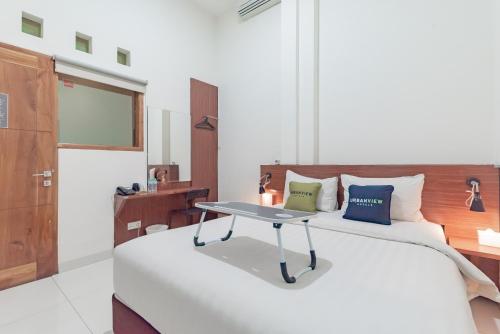 a bedroom with a bed with a table on it at Urbanview Darmo Residence Bandung in Bandung