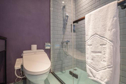 a bathroom with a toilet and a glass shower stall at CHECK inn HIVE in Luodong