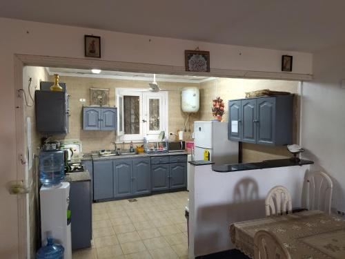 a kitchen with blue cabinets and a white refrigerator at Riviera Dream Chalet in Dawwār al Ḩajj Aḩmad