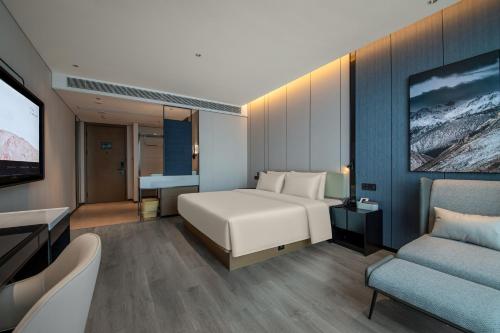 a bedroom with a bed and a couch and a tv at Atour Hotel Changshu Yunshang Town Mocheng Avenue in Changshu