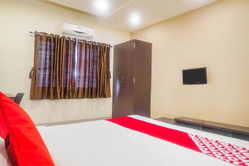 a bedroom with a bed and a tv on the wall at Hotel O Paradise Inn Talegaon Dabhade in Pune