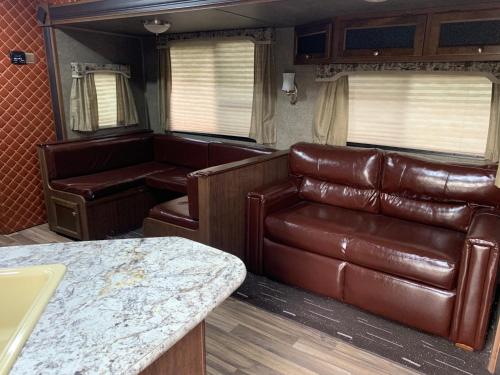 a living room with a leather couch and a table at Zhangjiajie Cliff Flower RV Tent Hotel in Sanguansi