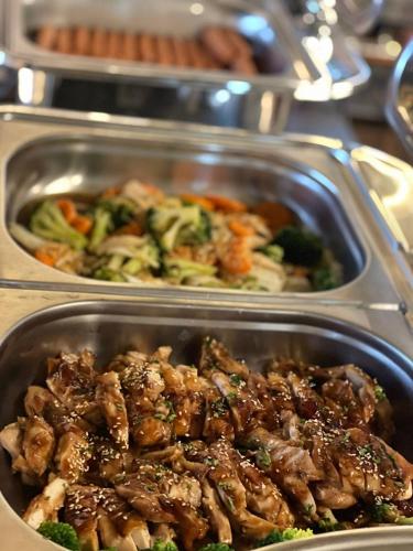 two trays of food with meat and broccoli on a table at Moji Don Mueang Airport Hotel - Bangkok in Bangkok