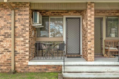 a porch with a table and chairs on a brick house at 2 Cute by Experience Jervis Bay in Huskisson