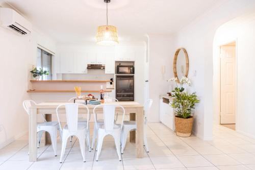 a dining room with a table and white chairs at Spacious Apartment, Walk To Kings Beach in Caloundra