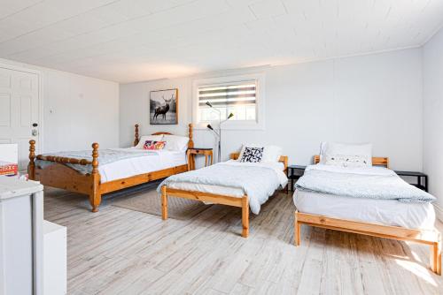 a bedroom with two beds and a bench in it at Luxury Beach Cottage - Maijac Resort & Marina in Burks Falls