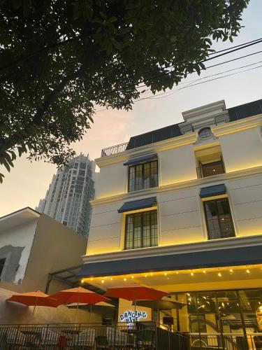 a building with tables and umbrellas in front of it at Luxeur Jakarta - Setiabudi in Jakarta