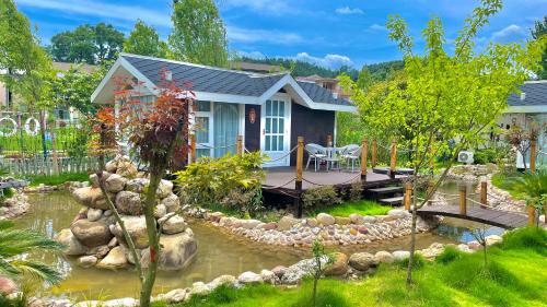 a small house with a pond in the yard at Zhangjiajie Cliff Flower RV Tent Hotel in Sanguansi