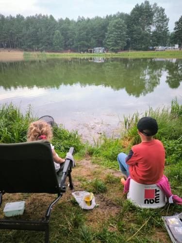 two children sitting on chairs by a lake at Roztoczańska Przystań in Majdan Sopocki